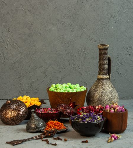 front view yellow and light green nogul candies with spices and dried flowers with a vase